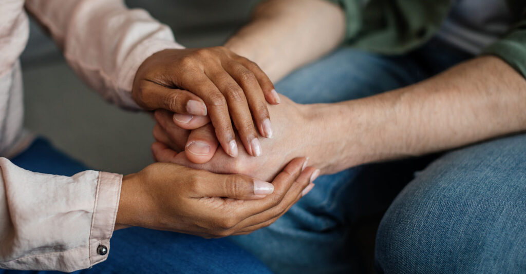 Cropped young african american woman doctor holding hands with patient supporting client at meeting in office clinic interior, close up. Psychological therapy, session with professional, mental help